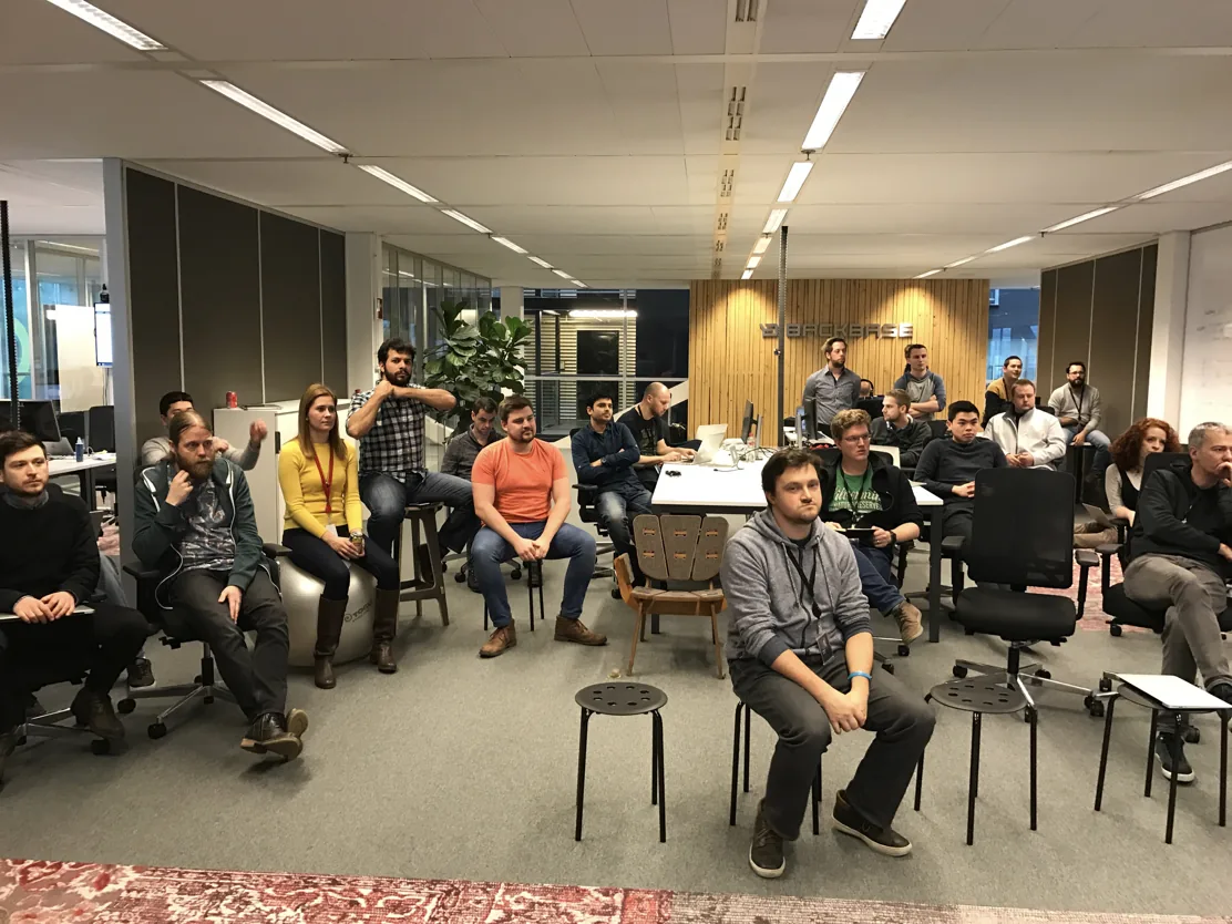 Photo of Sprint Review attendees seated in an open office, watching one team present in the traditional format