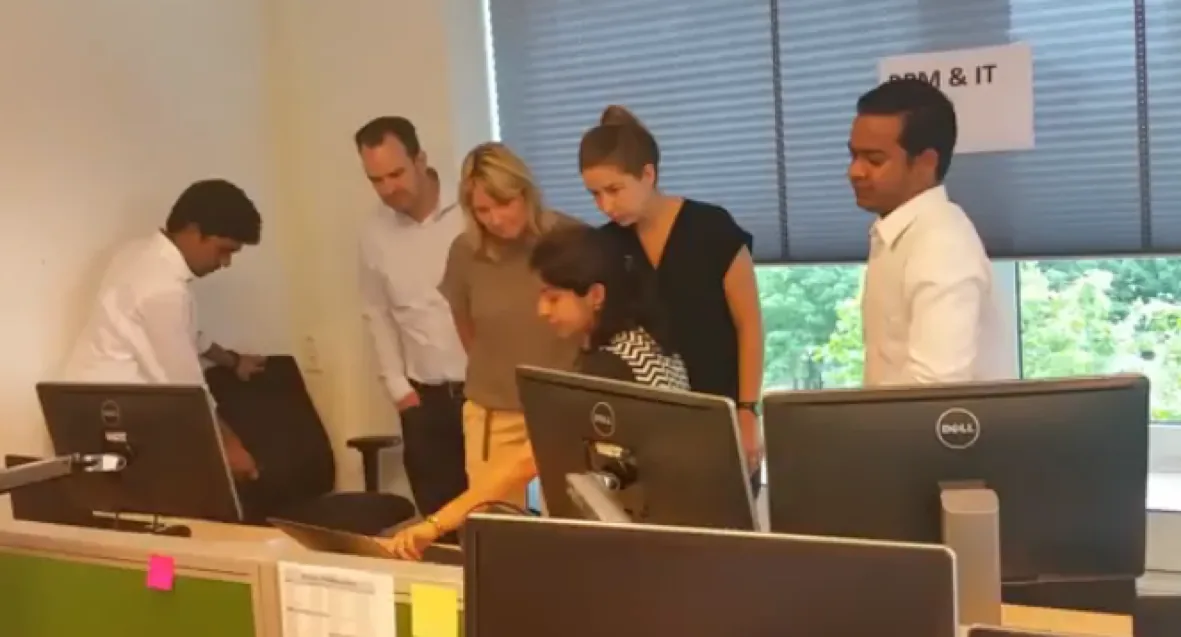 Stakeholders and team members gathered around a screen at a feature shop during the Sprint Review bazaar
